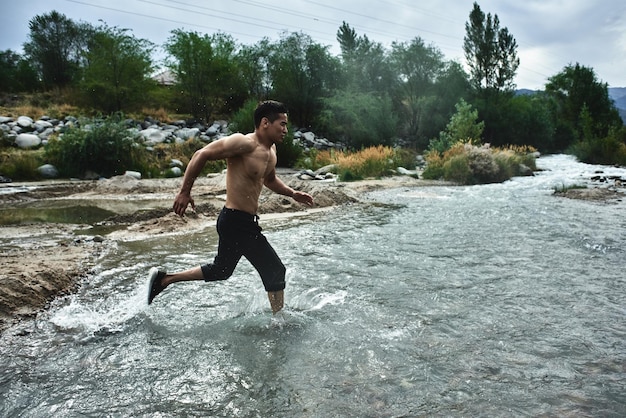 Atleta asiático en una carrera matutina en el río, jogger kazajo en primer plano de la naturaleza