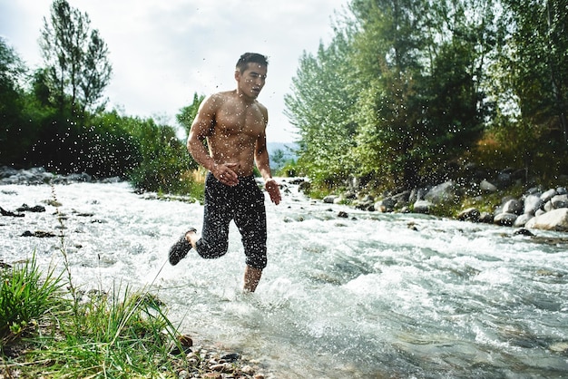 Atleta asiático em uma corrida matinal no rio, corredor cazaque em close-up da natureza