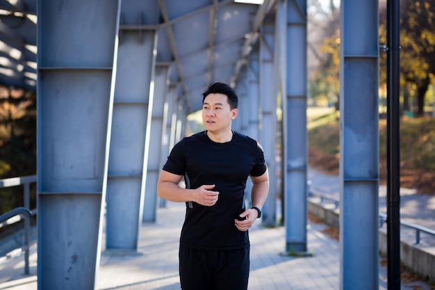 Atleta asiático em uma corrida matinal perto do estádio empresário masculino bem sucedido está envolvido em fitness de manhã antes do trabalho