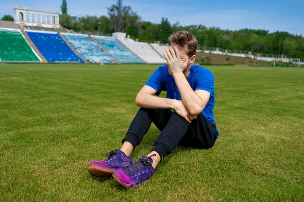 Foto atleta atleta masculino cansado relaxando no gramado após os treinos