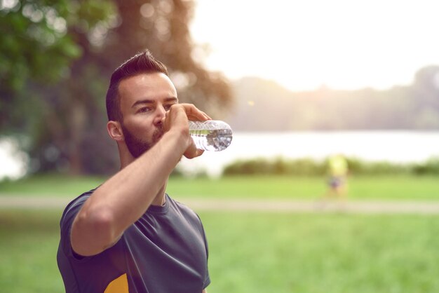 Atleta bonito a beber água no parque.