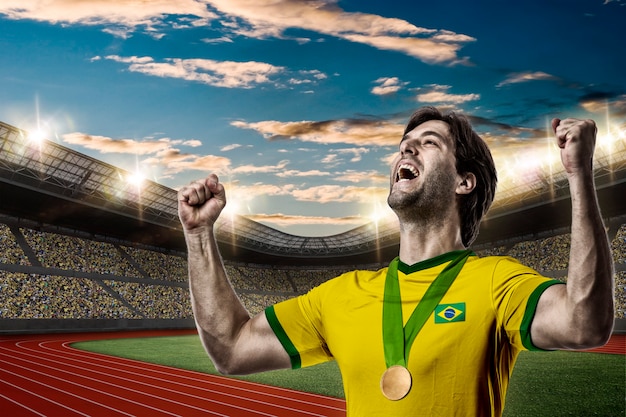 Atleta brasileño ganando una medalla de oro en un estadio de pista y campo.