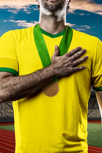 Atleta brasileño ganando una medalla de oro en un estadio de pista y campo.