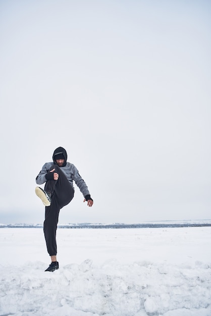 Atleta calentando en invierno en la naturaleza.