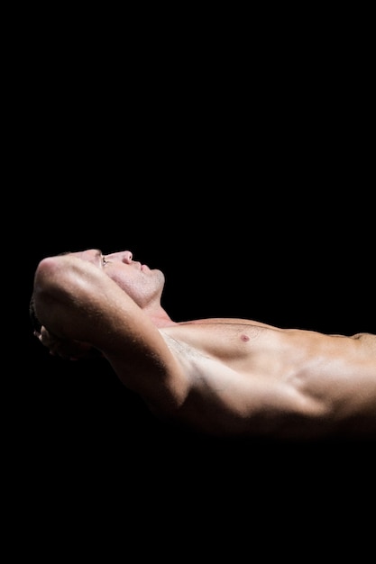 Foto atleta sin camisa en el aire mirando hacia arriba contra el fondo negro