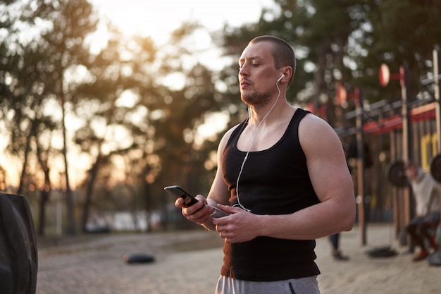 Atleta caucásico adulto joven escuchando música de teléfono