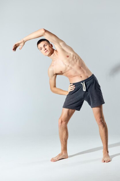 Atleta com músculos do braço inflados dobrados para o lado em um exercício de fundo cinza