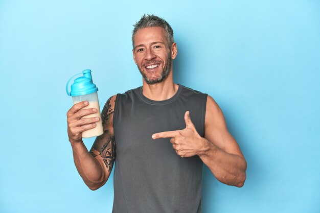 Foto atleta com shake de proteína no pano de fundo azul do estúdio