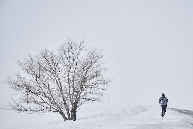 El atleta corre en el invierno en la carretera.