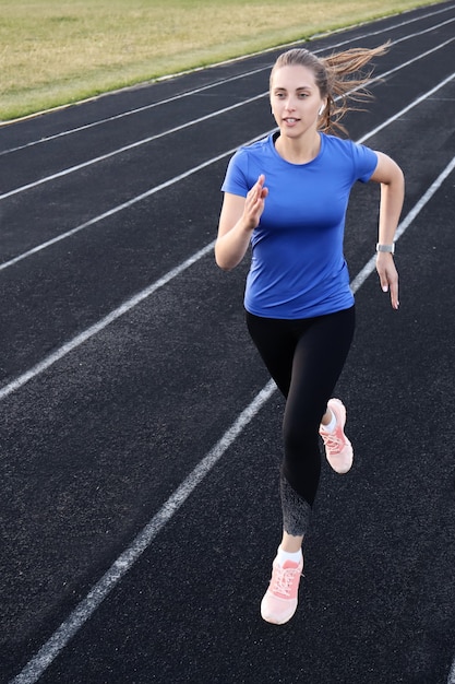 Foto atleta corredor corriendo en pista de atletismo entrenando su cardio en el estadio. trotar a un ritmo rápido para la competición.