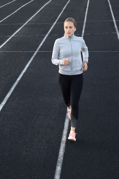 Atleta corredor corriendo en pista de atletismo entrenando su cardio en el estadio. Trotar a un ritmo rápido para la competición.