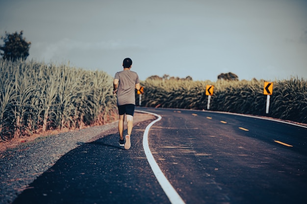 Foto atleta corredor hombre en el camino hacia la salud, los jóvenes ejecutan ejercicio en la calle