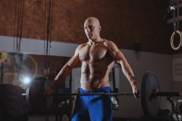 Atleta de crossfit masculino fuerte ejercicio con barra pesada