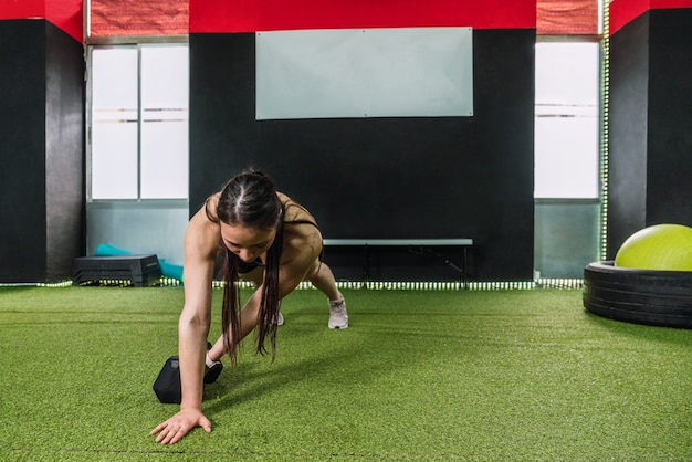 Atleta culturista femenina caucásica haciendo ejercicios de tonificación con pesas rusas en un gimnasio. Culturista femenina haciendo rutina de entrenamiento crossfit con ropa deportiva en un gimnasio