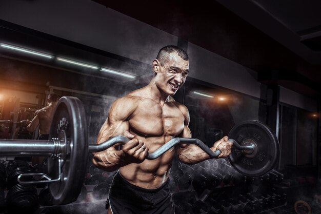 Foto atleta culturista musculoso en el gimnasio entrenando con una barra