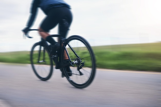 Atleta de bicicleta de pessoa e ciclismo em desfoque de movimento no campo da natureza e treinamento para triatlo por trás da bicicleta de montanha do ciclista e velocidade na estrada para poder esportivo ou corrida de competição cardio