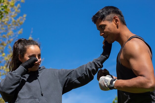 Atleta de boxe profissional jovem e poderosa, engajada com seu personal trainer na rua durante a preparação para uma competição. Copie o espaço