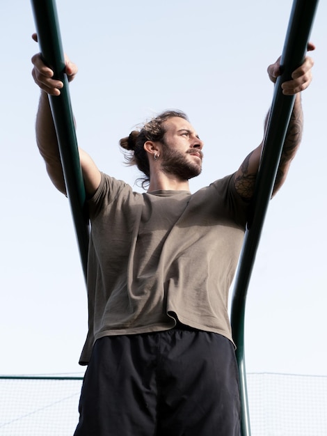 Atleta de calistenia caucasiana com cabelo comprido e barba nas barras paralelas