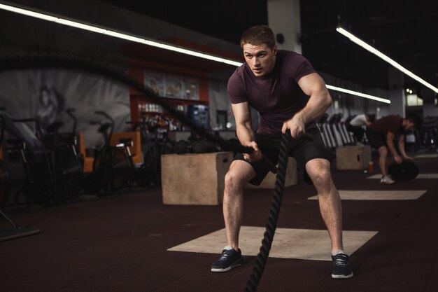 Atleta de cross fit malhando com cordas de batalha na academia