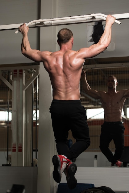 Atleta de fisiculturismo masculino fazendo pull ups