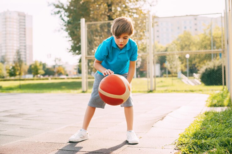 Atleta de menino bonito focado conduz a bola em um jogo de basquete.