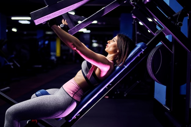 Atleta de mulher atraente meia idade fazendo exercícios nos músculos peitorais no simulador. Gym Machine
