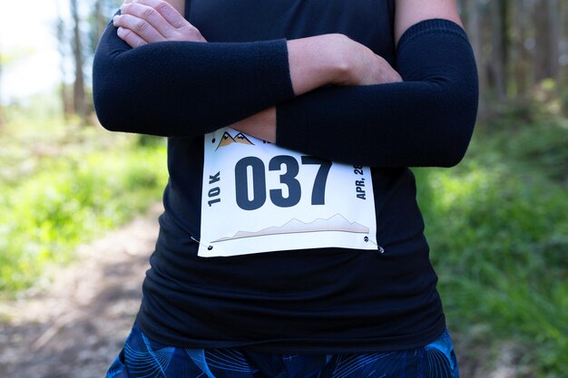 Atleta de trilha feminina irreconhecível posando com número de corrida