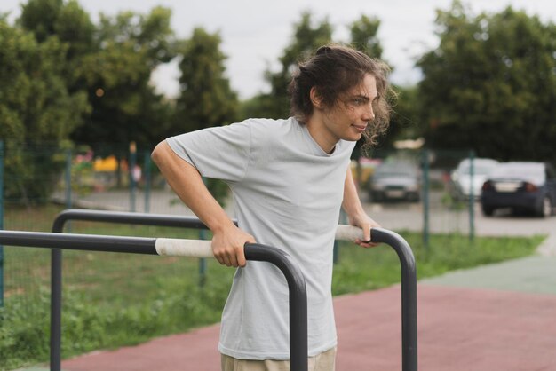 Foto un atleta decidido haciendo ejercicios de potencia en el parque flexiones sobre las barras de metal