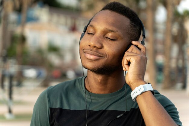 Atleta desportista masculina aproveita o verão e ouve música agradável em fones de ouvido