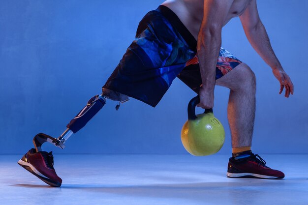 Atleta con discapacidad o amputado aislado en pared azul.