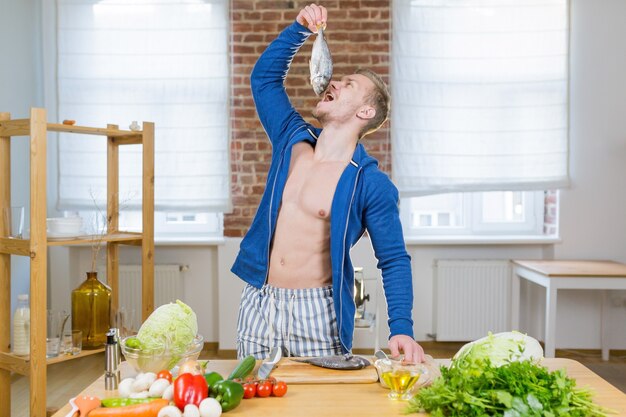 Atleta do sexo masculino prepara peixe na cozinha de casa