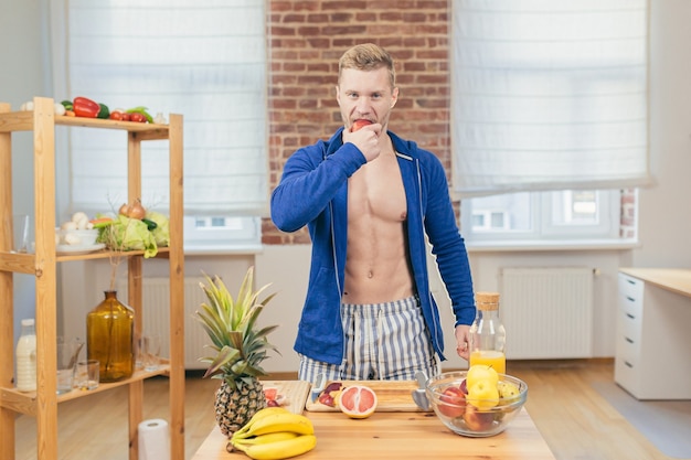 Atleta do sexo masculino prepara salada e suco de frutas frescas em casa na cozinha