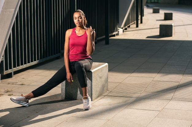 Atleta em forma bonita sentada sozinha ao ar livre com roupas esportivas