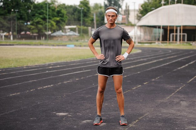 Atleta em pé com a mão na pista de corrida quadril