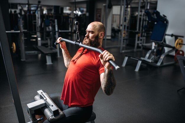 Atleta em roupas esportivas, treinando na máquina de exercícios no ginásio.