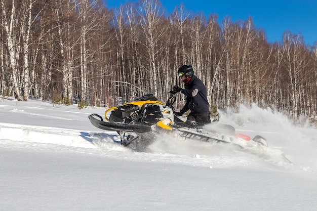 Atleta em um snowmobile na floresta de inverno.