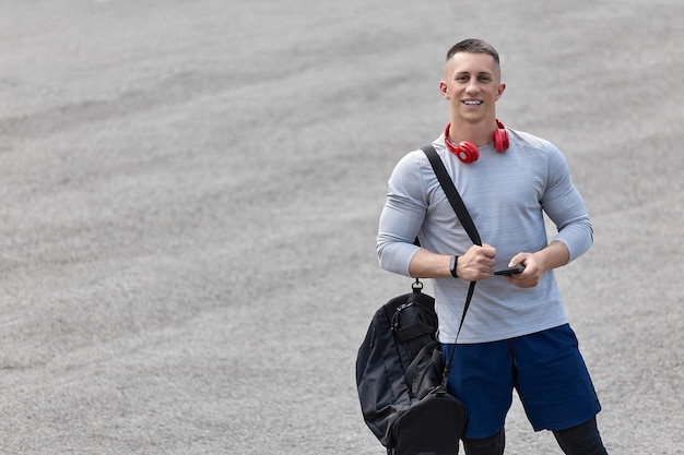 Atleta em uniforme esportivo sorri após terminar o treino e sai do estádio