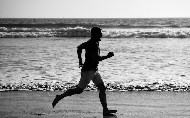 Foto atleta esportivo corre rápido para ganhar na atividade de treino matinal do oceano homem saudável correndo na praia