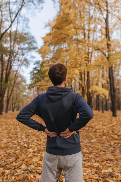 Atleta esportivo irreconhecível se alongando e se aquecendo antes de treinar no outono na natureza