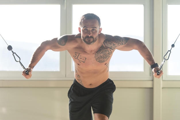 Atleta está trabajando en su pecho con cable cruzado en el gimnasio