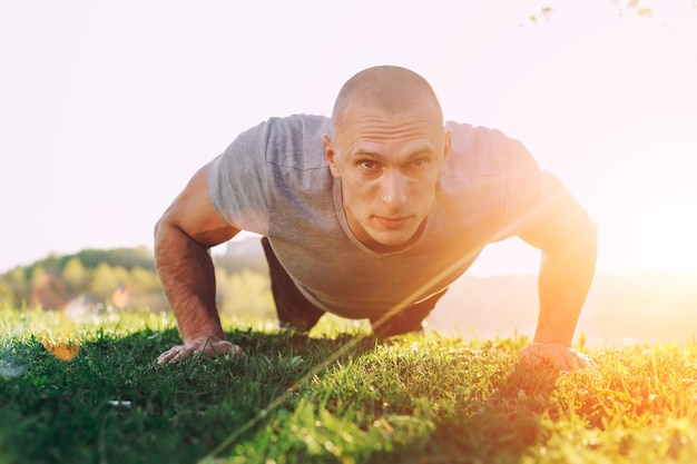 Atleta fazendo aperto ao pôr do sol no parque