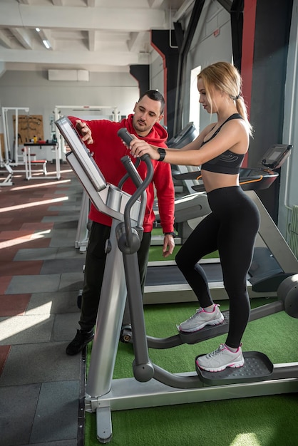 Atleta femenina con asistente de entrenador personal corriendo en cintas de correr Personas entrenan en el gimnasio