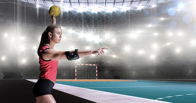 Atleta femenina con codera lanzando balonmano contra el campo de balonmano interior