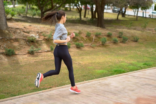 Foto atleta femenina corriendo sola en la vista trasera de park road