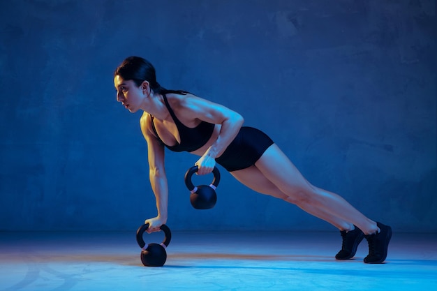 Atleta femenina joven caucásica practicando en azul en luz de neón