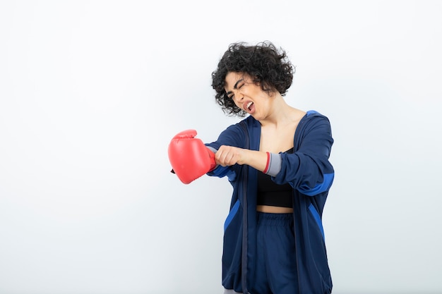 Atleta femenina de pelo rizado quitándose los guantes rojos.