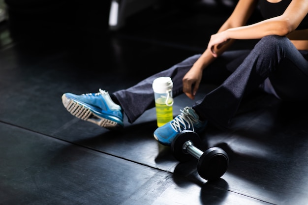 Atleta femenina tomando descanso después de hacer ejercicio en el gimnasio. Fitness estilo de vida saludable y entrenamiento en el concepto de gimnasio.