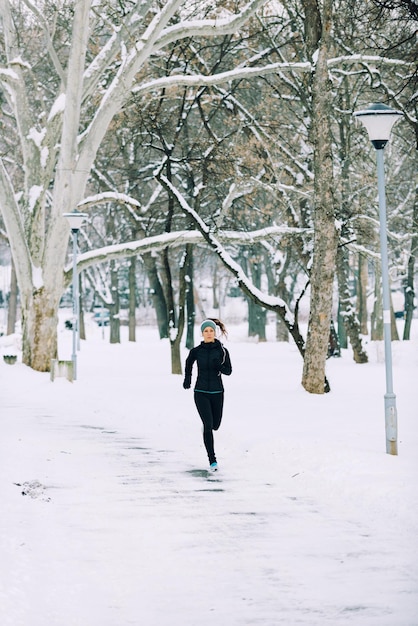 Atleta femenina trotando en el parque en invierno