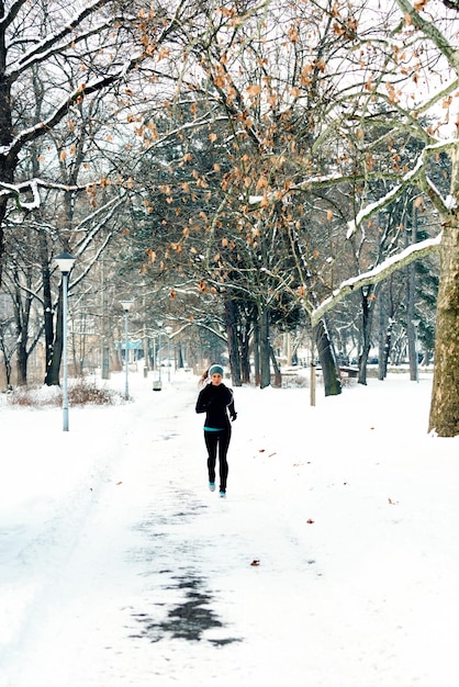 Atleta femenina trotando en el parque en invierno