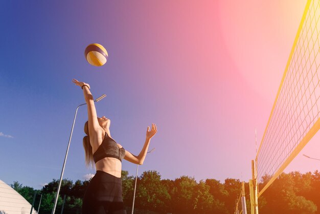 Una atleta femenina de voleibol de playa con una pelota en la cancha de voleobol